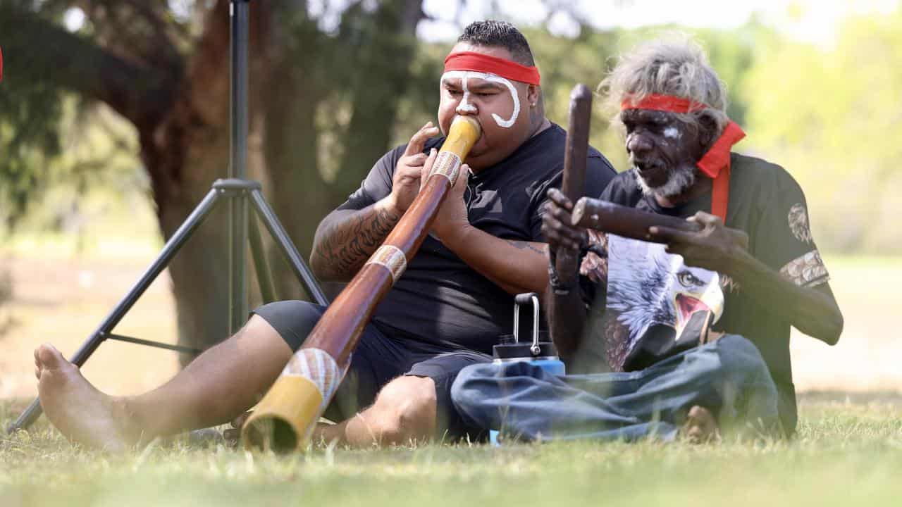 Two men play traditional instruments.