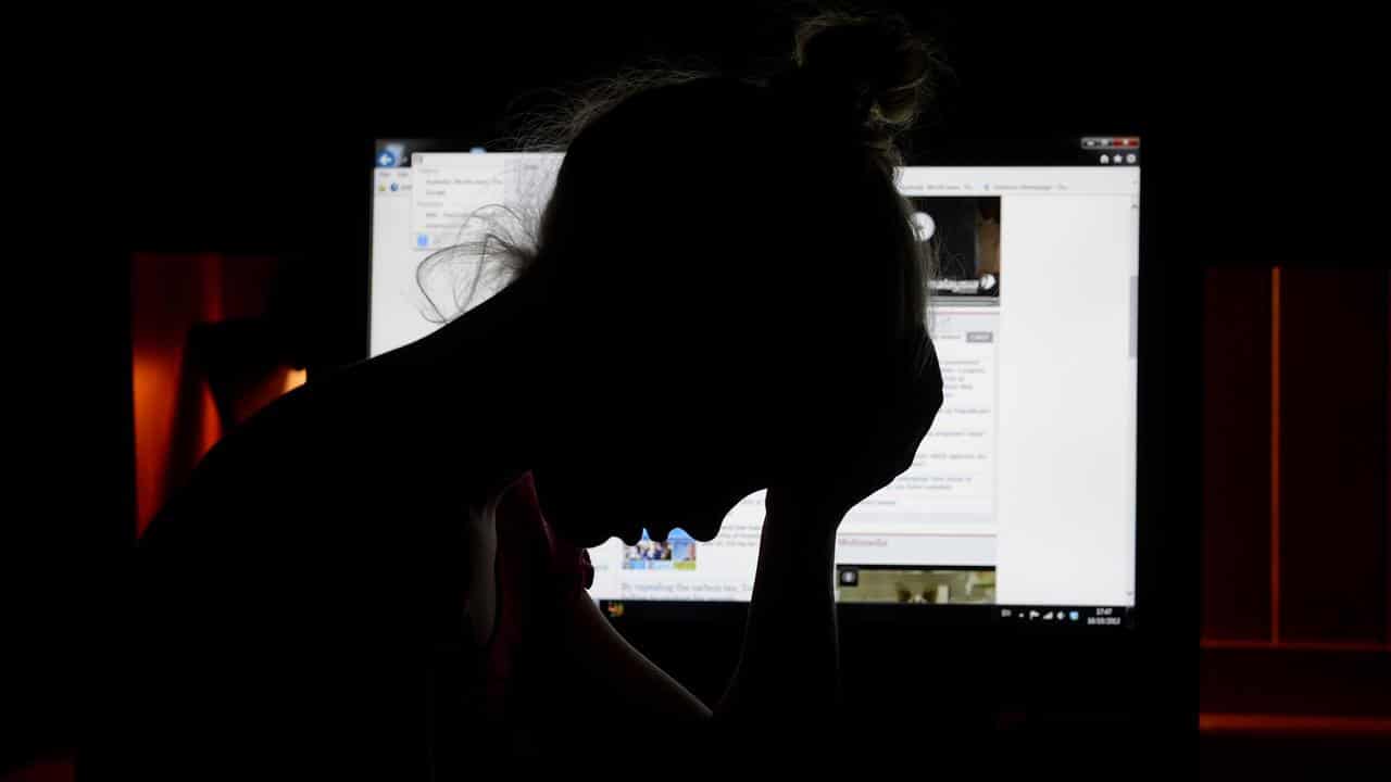 A distressed girl on a phone in front of a computer