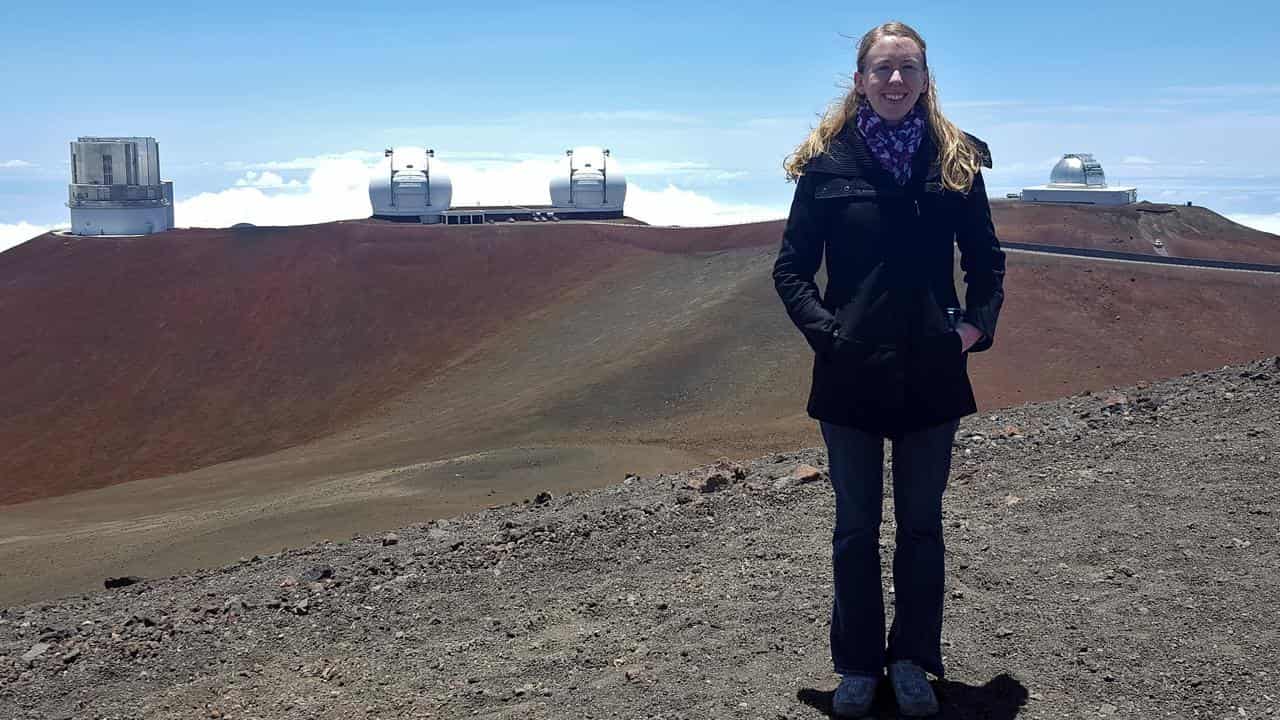 A person stands in front of an observatory.