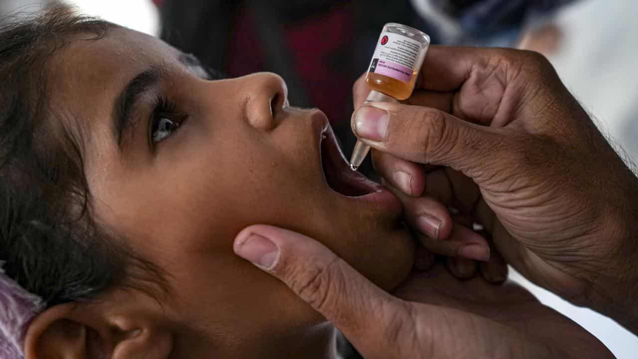 A health worker administers a polio vaccine to a child