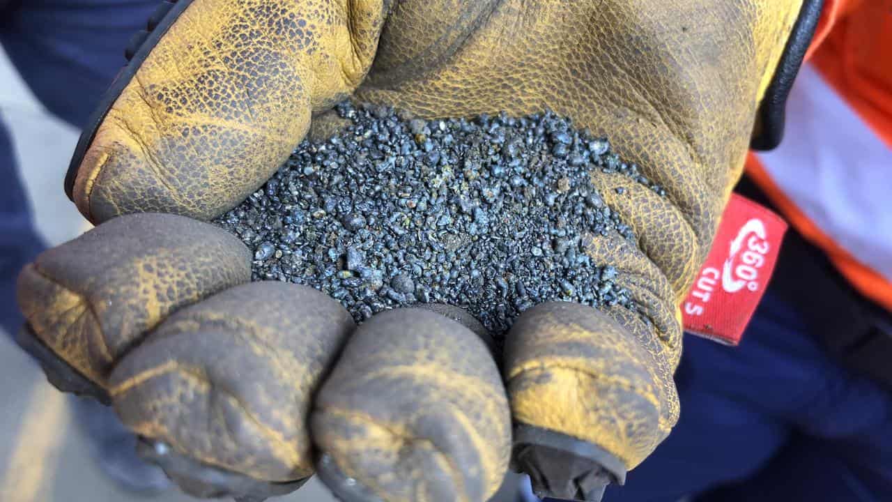 Nickel granules in a gloved hand.