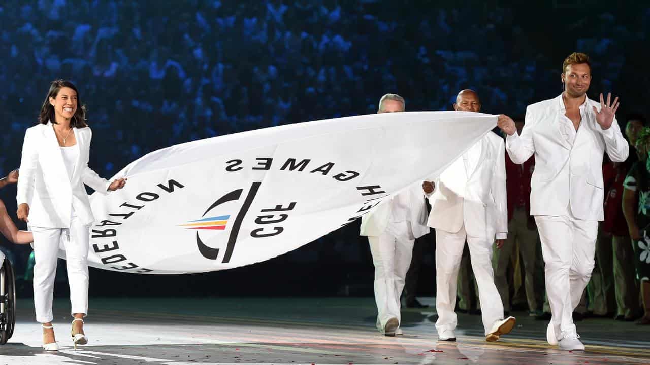 Athletes carry the Commonwealth Games Federation flag.