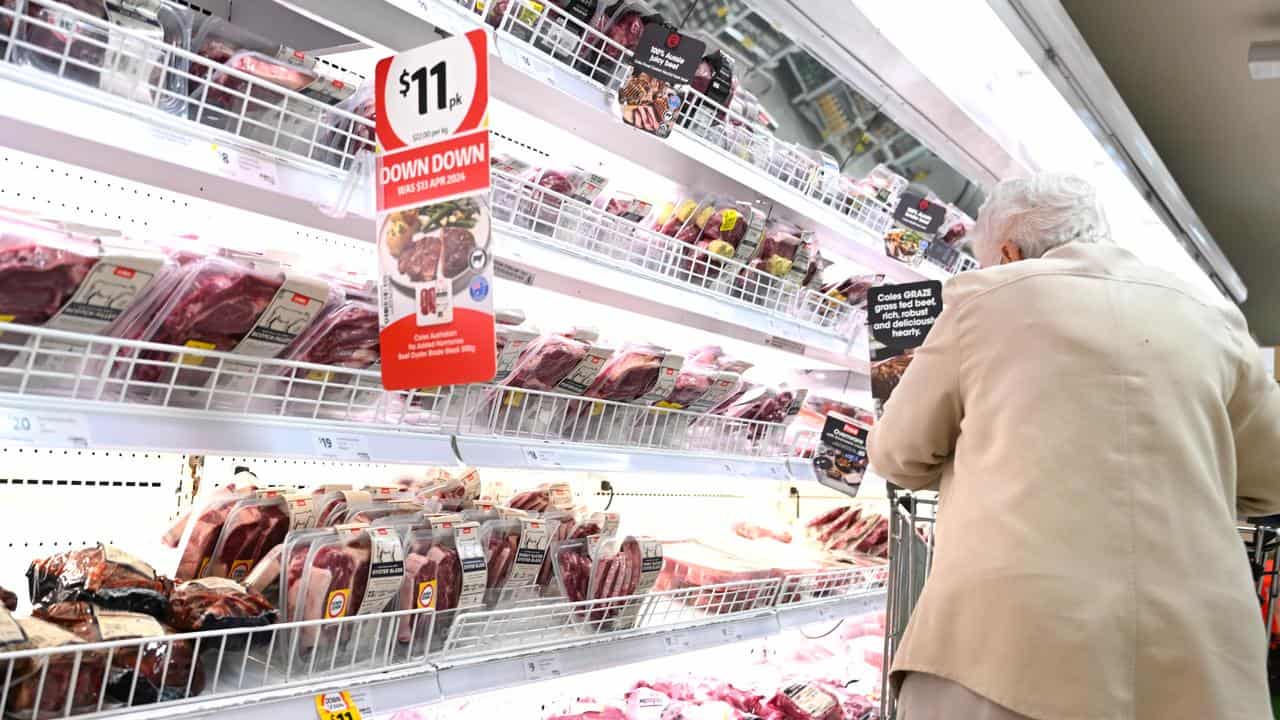 A woman is seen shopping for meat at a Coles supermarket