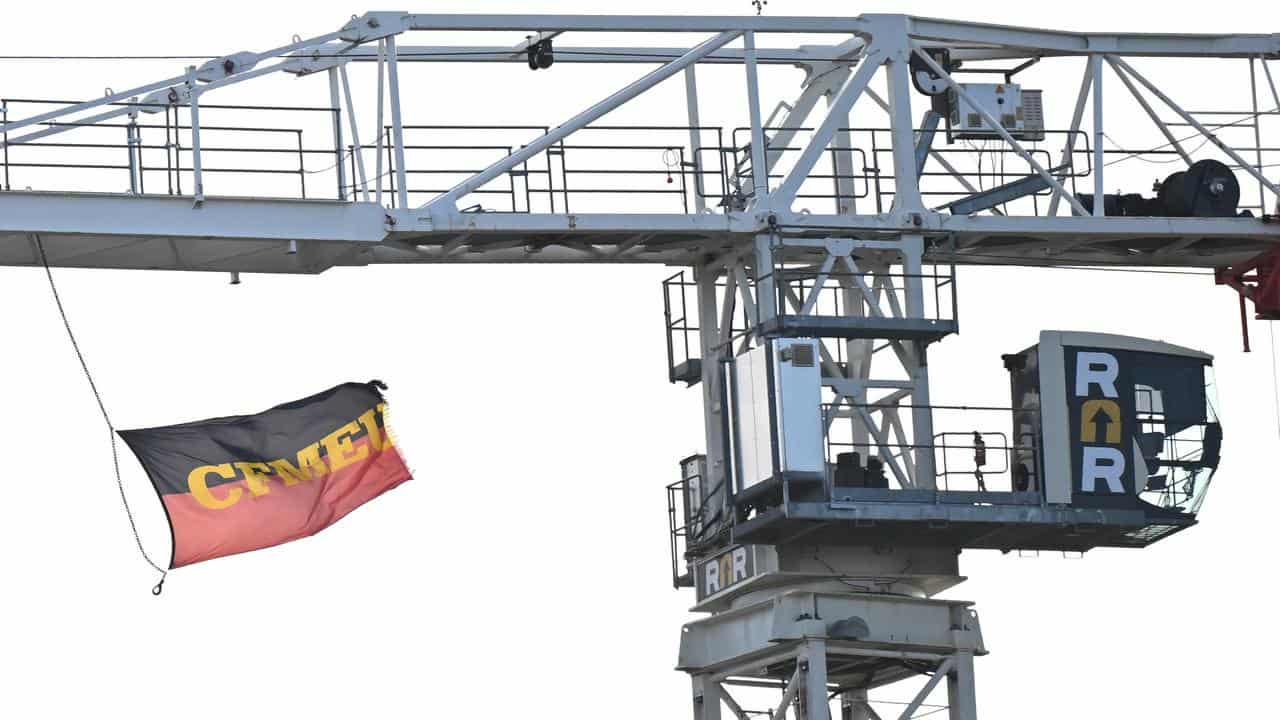 A CFMEU flag is seen flying from a tower crane