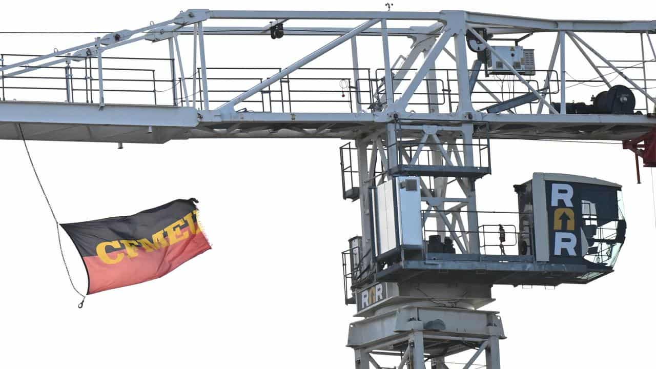 A CFMEU flag is seen flying from a tower crane