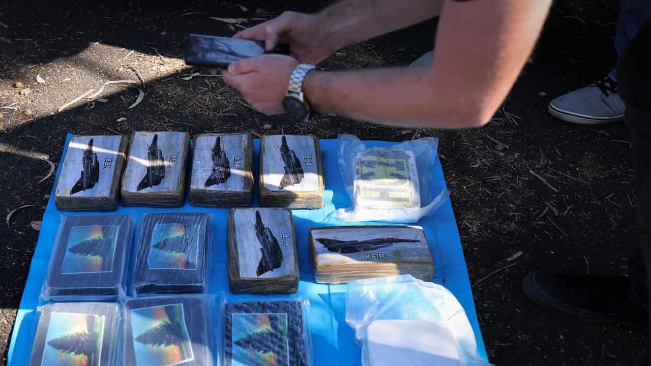 An officer examines drug packets found hidden in a car