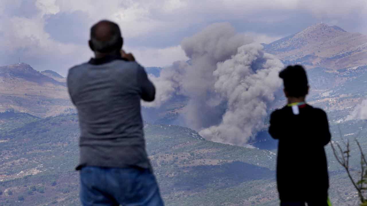 Lebanese citizens watch the smoke of Israeli air strikes