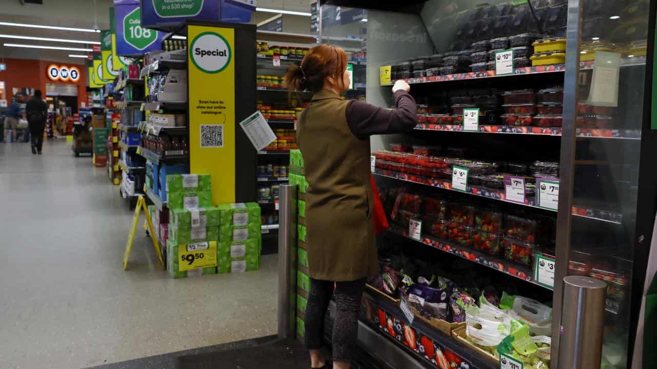 A shopper selects fresh produce at Woolworths supermarket in Melbourne