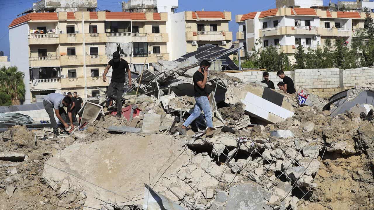 People at the site of an Israeli air strike in Jiyeh