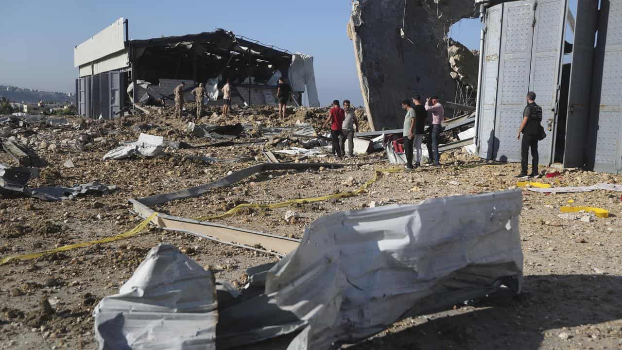 People gather at the site of a hangar hit by a strike in Jiyeh