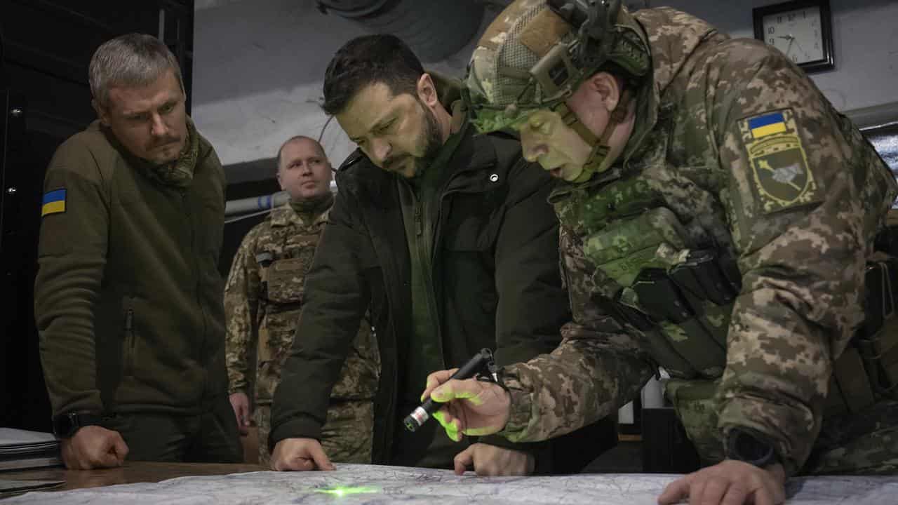 Ukrainian President Volodymyr Zelenskiy looks at a map in Kupiansk