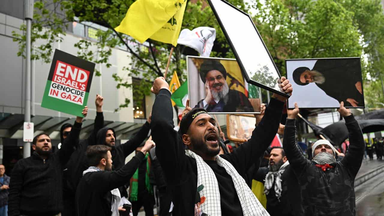 A protester in Melbourne with a photo of Hezbollah's Hassan Nasrallah