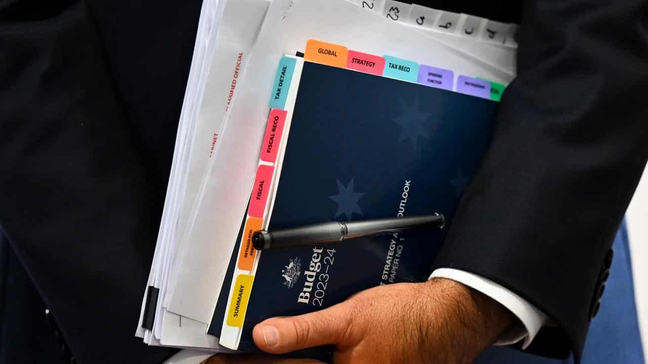 Treasurer Jim Chalmers holds a copy of the Budget papers