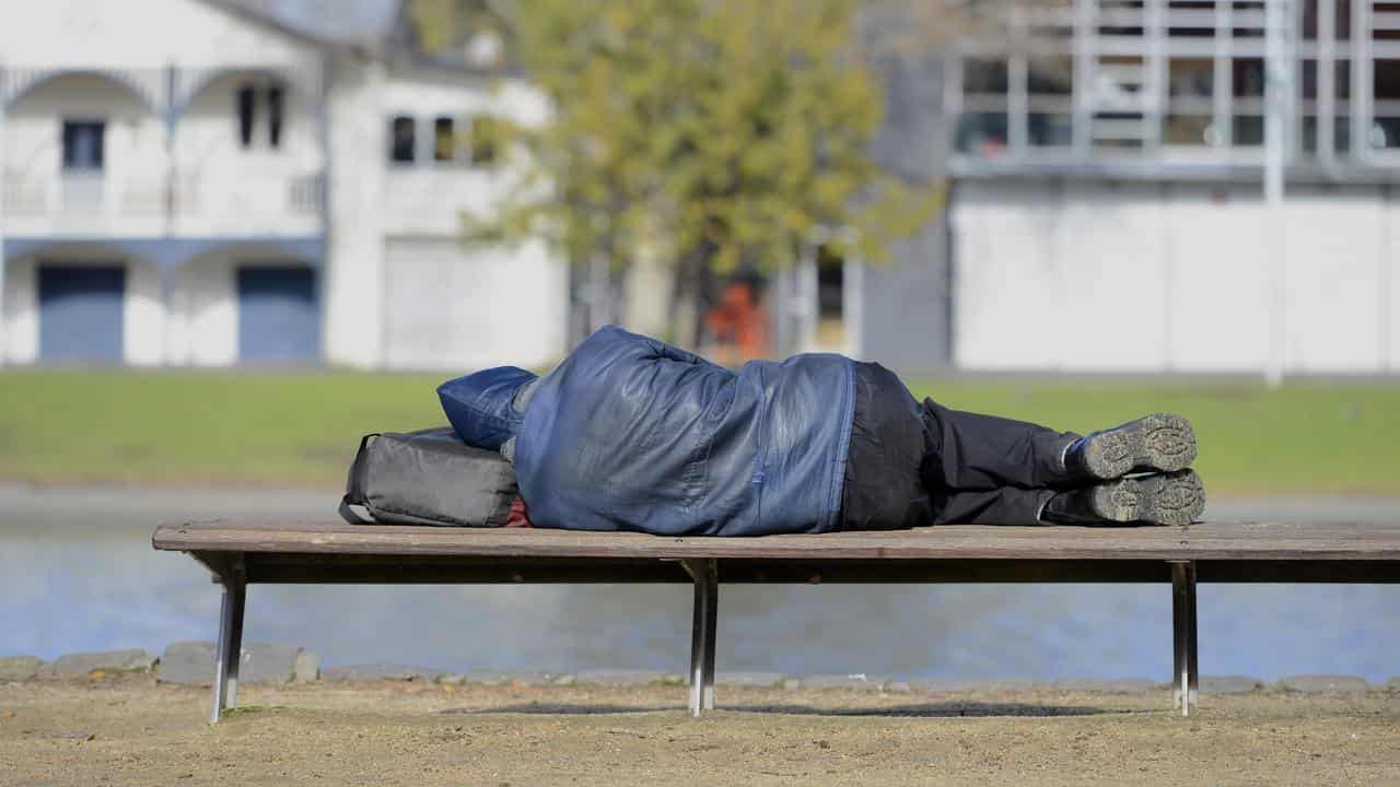 Homeless man sleeps on a bench