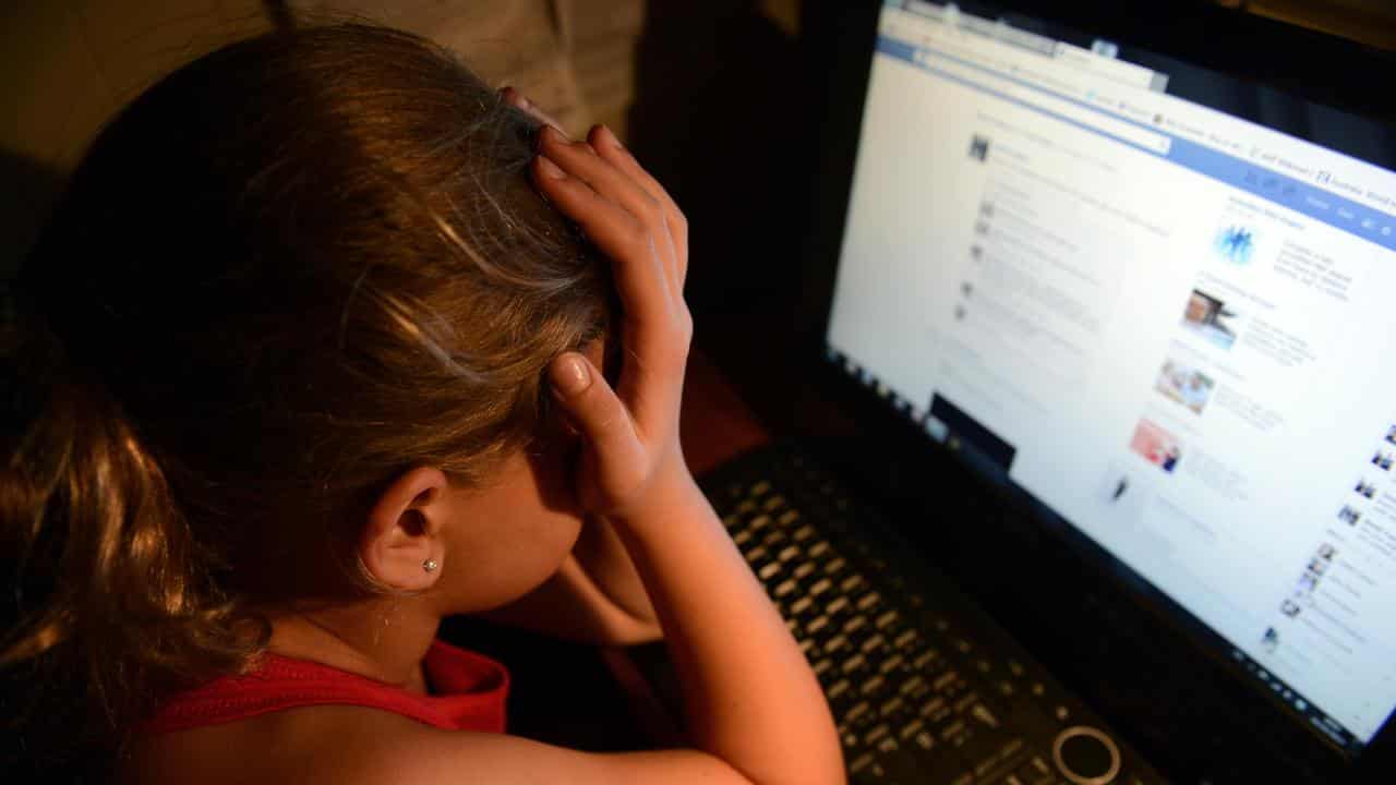 An upset young girl in front of a personal computer