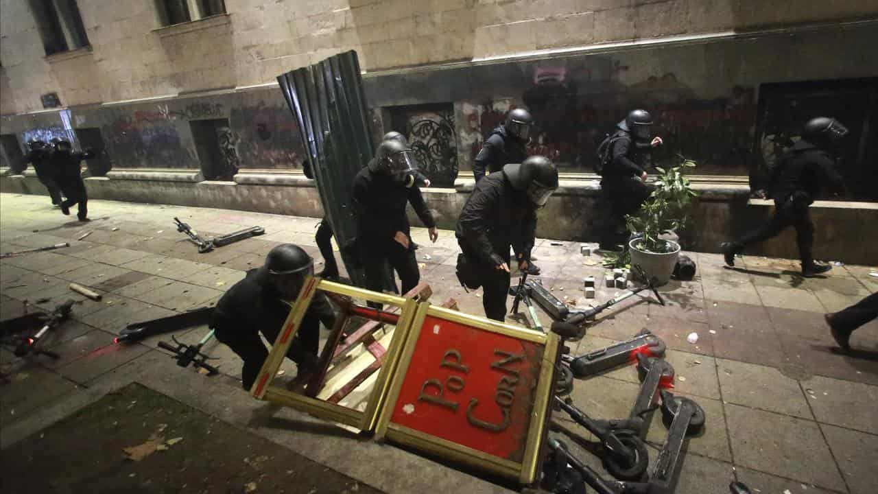 Police run through a barricade built by demonstrators