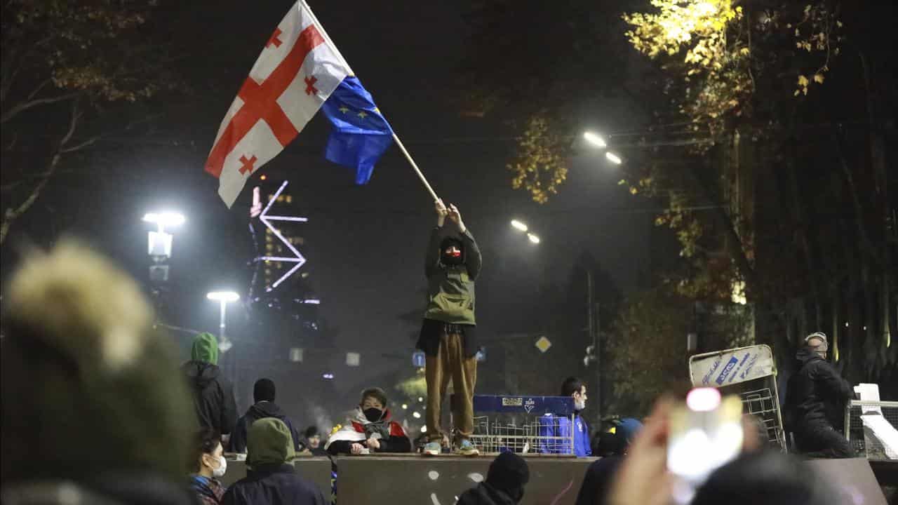 A demonstrator stands with Georgian national and EU flags