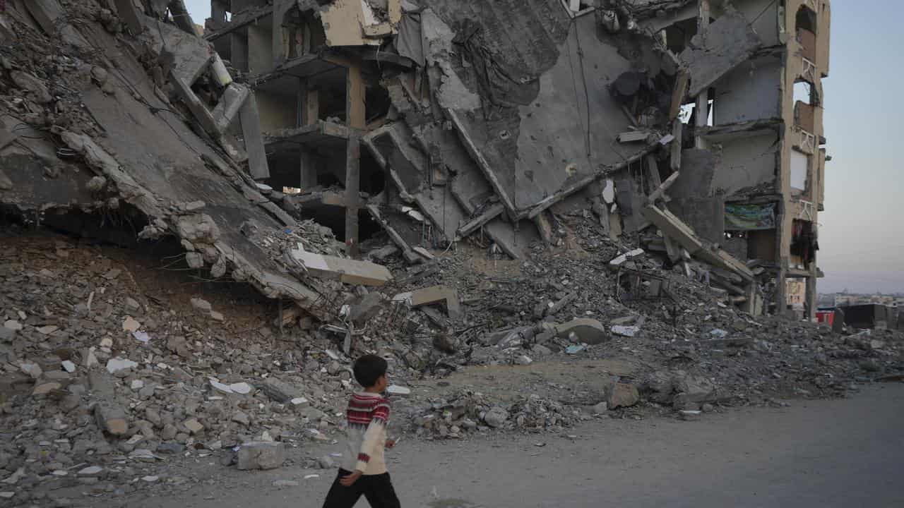 Boy walks past destroyed building in Khan Younis