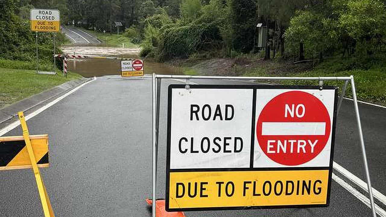 A sign warning against entering floodwaters during heavy rain in Qld