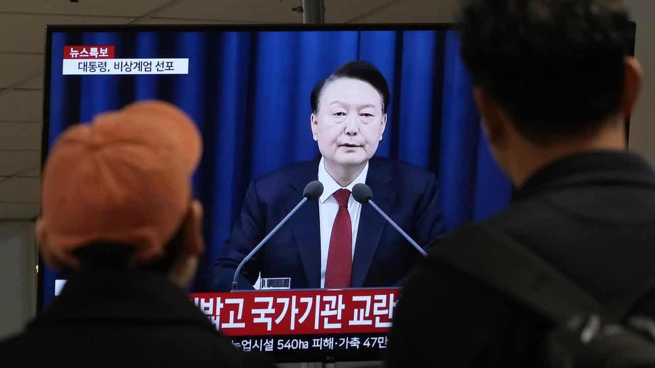 People watch a TV showing South Korean President Yoon Suk-yeol