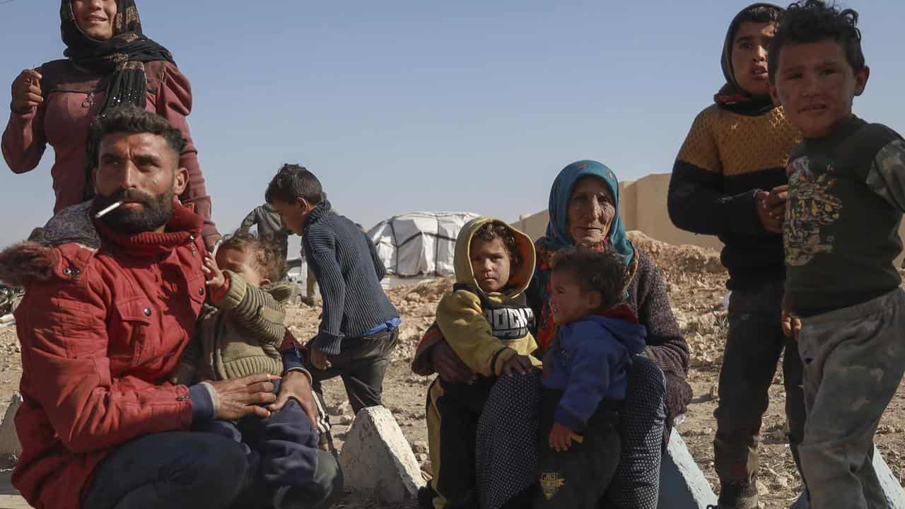 Internally displaced people sit in a camp in Tabqa city, Syria