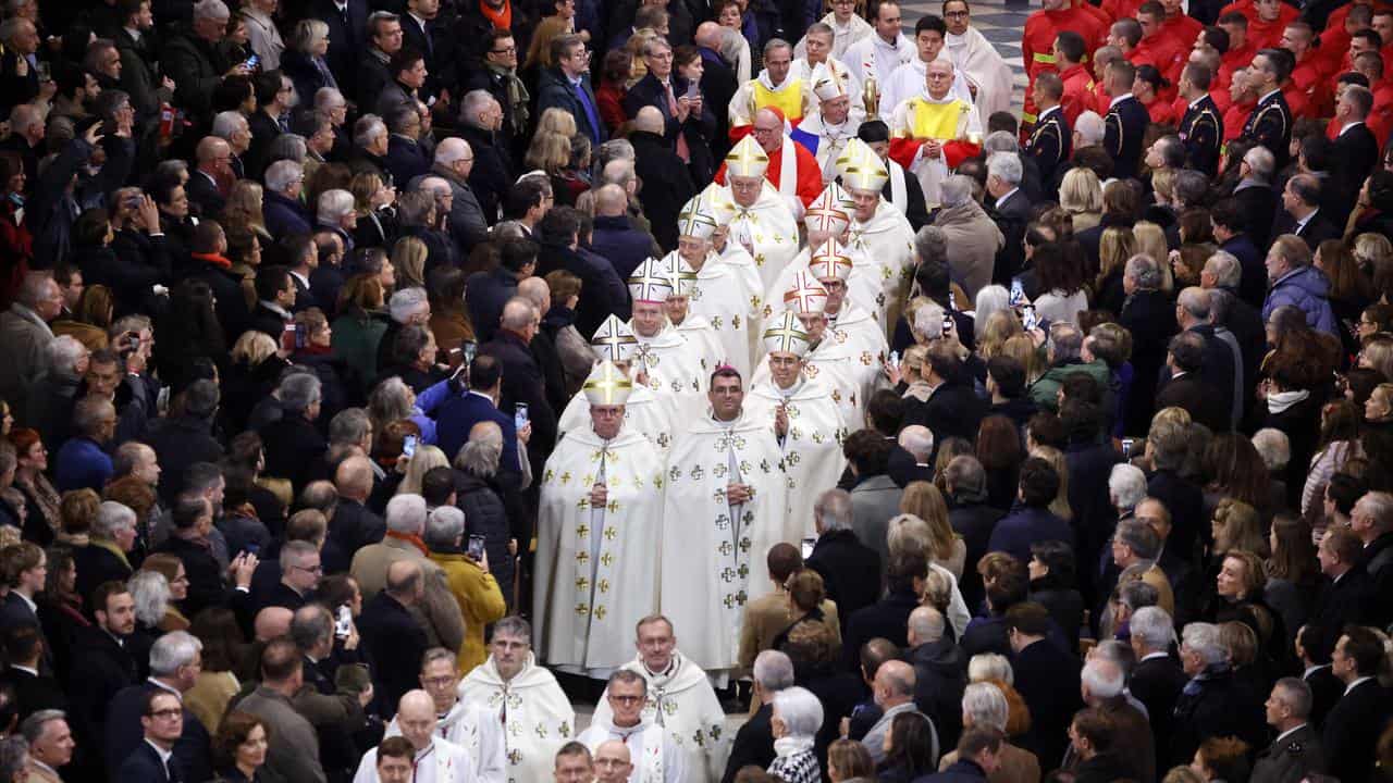 Guests stand as clergy walk down the isle in Notre Dame Cathedral