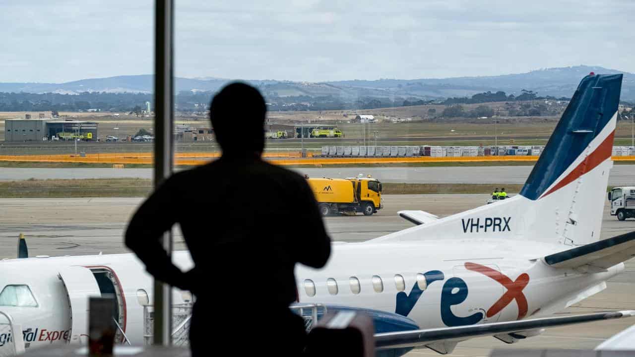 Person views Rex plane from inside airport terminal