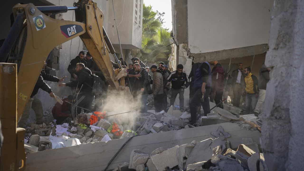 Palestinians search in the rubble of a building