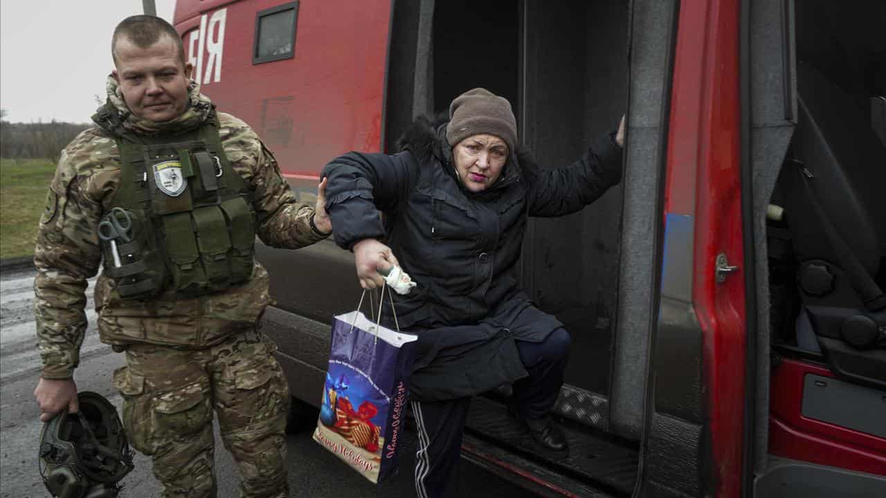 A police officer helps a woman during the evacuation of Pokrovsk