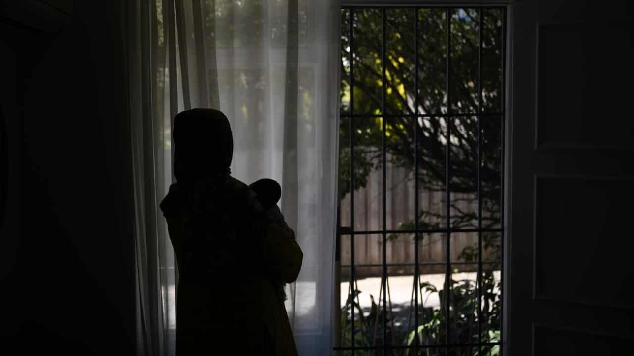 A woman stands holding a child