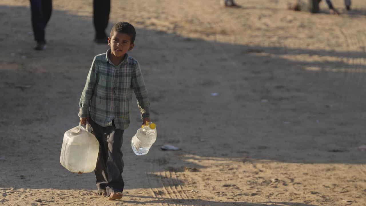 A Palestinian boy carries water in Khan Younis, Gaza Strip