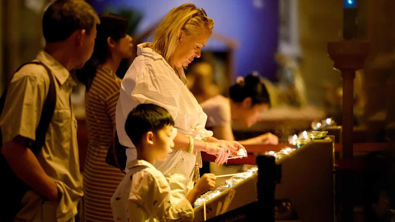 People in a church lighting candles 