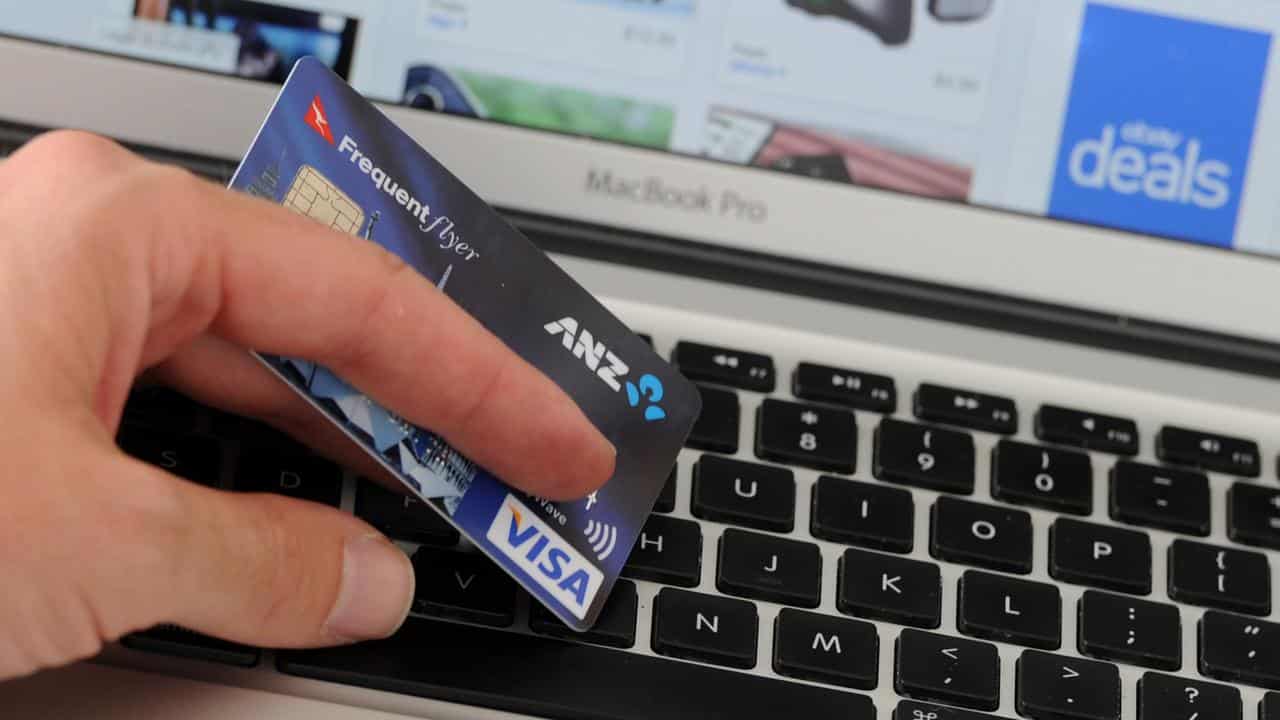 A credit card is held in front an online shopping site (file image)