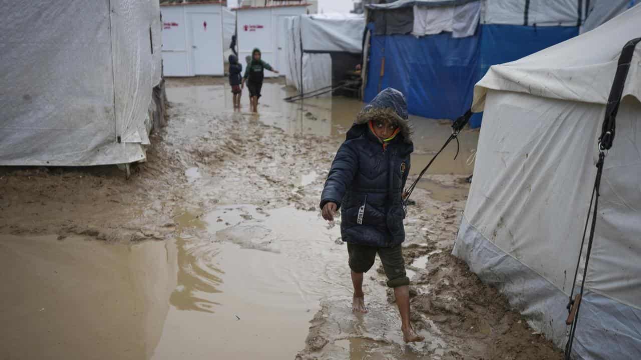 Boy walks through mud in a refugee camp