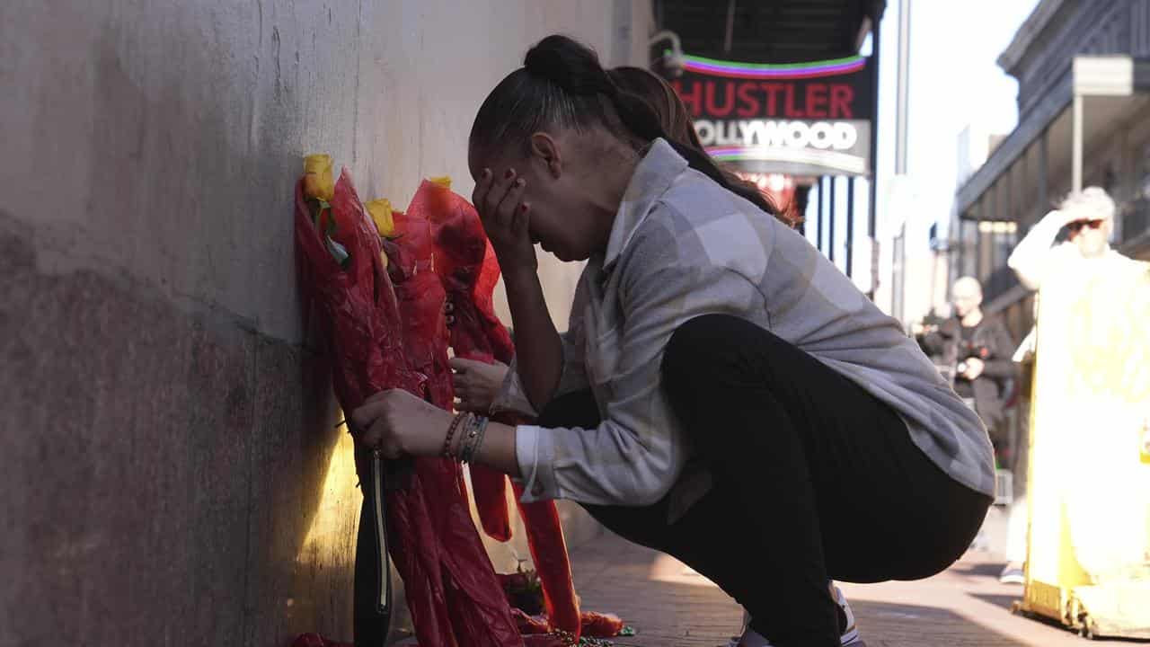 A woman places flowers at a memorial on Bourbon Street, New Orleans