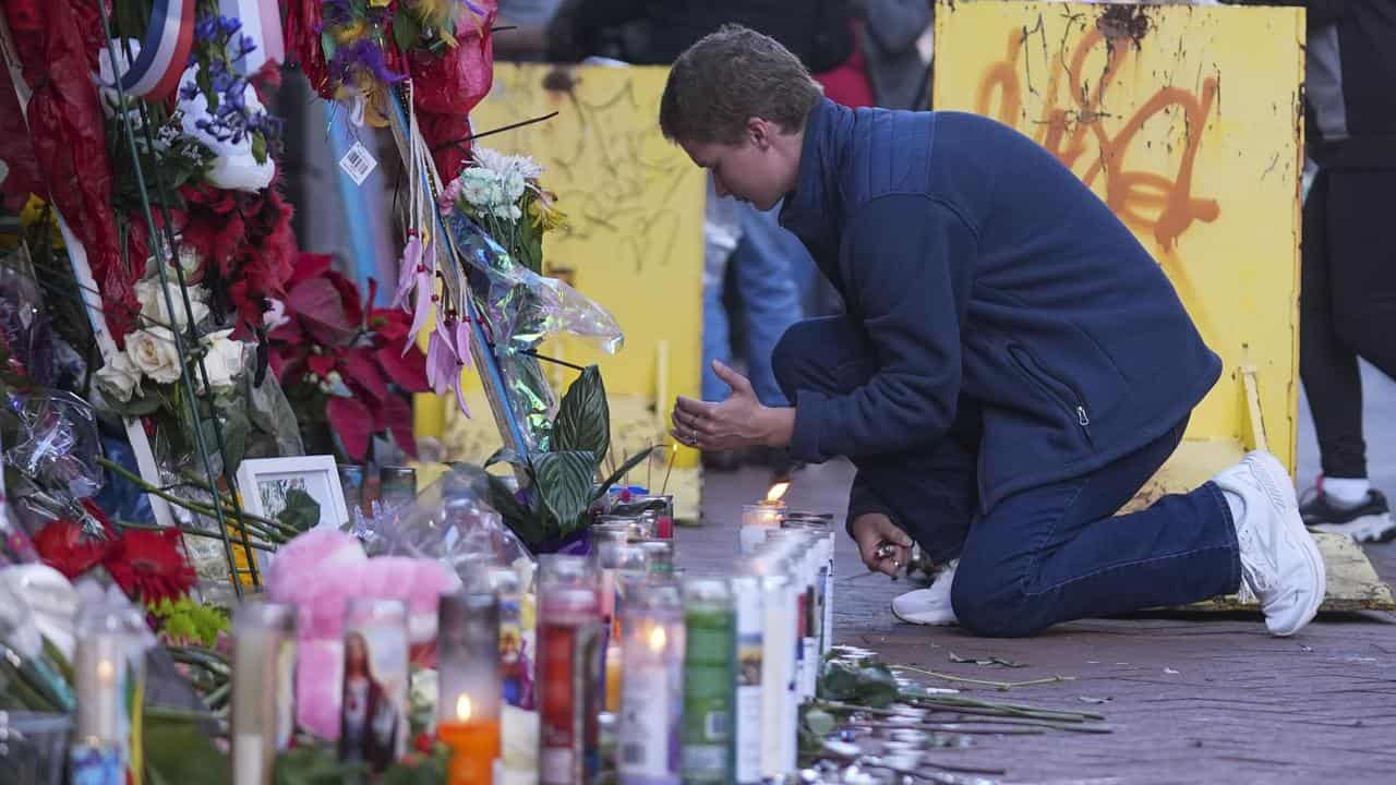 A person lights a candle at a memorial