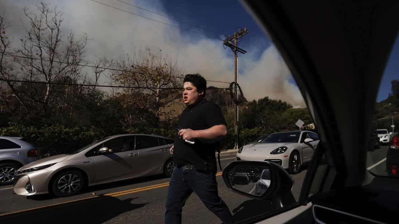 A person fleeing from a wildfire in the Pacific Palisades neighborhood