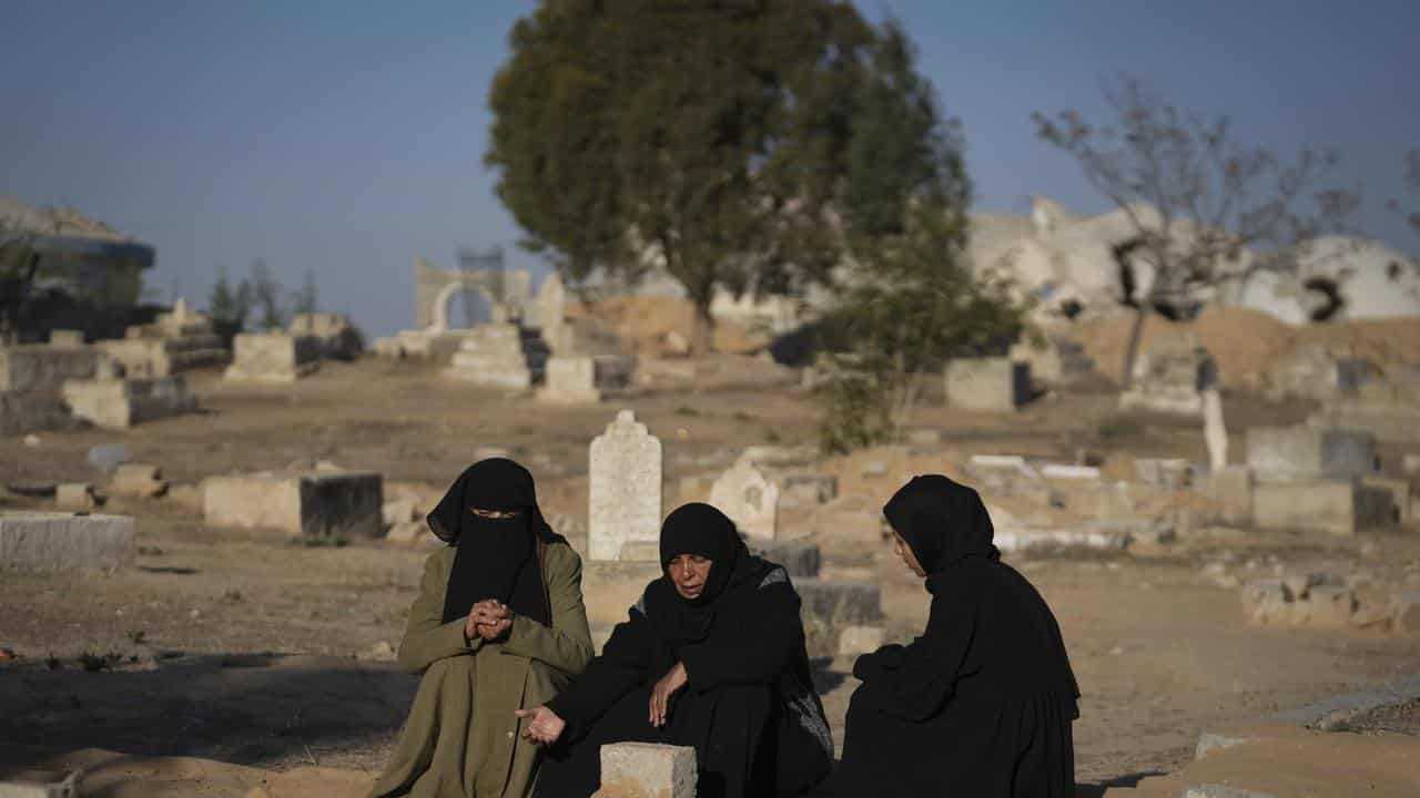 People pray after their relatives were killed in an Israeli strike