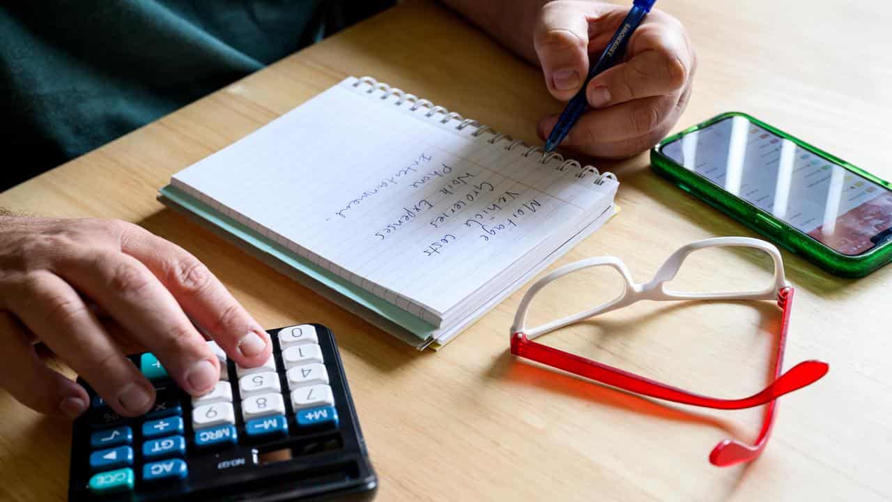 A person using a calculator to determine a  household budget