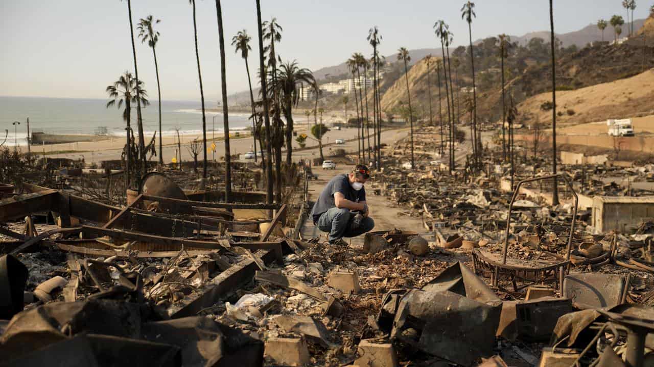 A man sifts through his mother's fire-ravaged property in Los Angeles