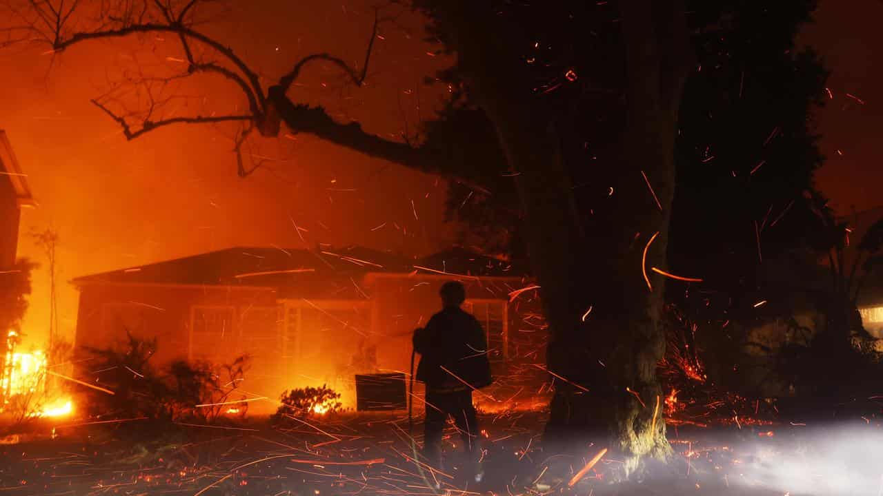 A person hoses down embers from the Los Angeles fires.