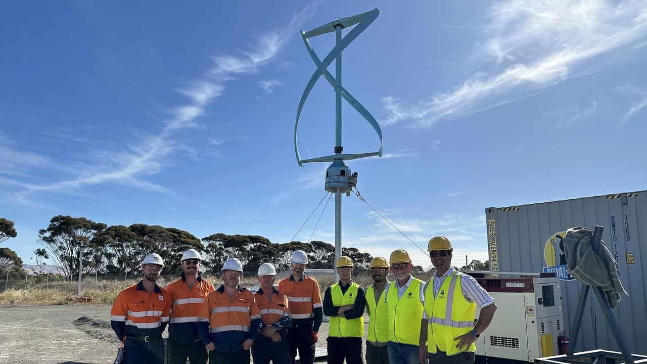 Researchers and VAWT-X Energy representatives with the wind turbine