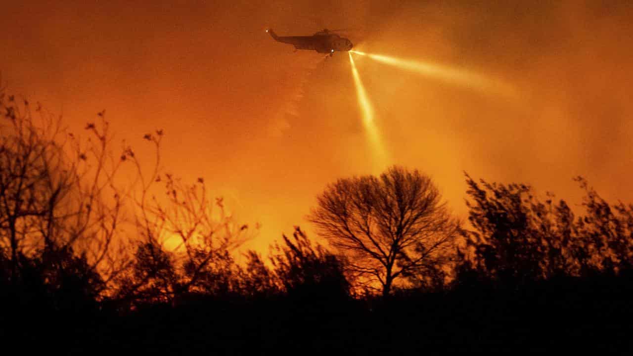 A helicopter drops water on the Auto Fire in California