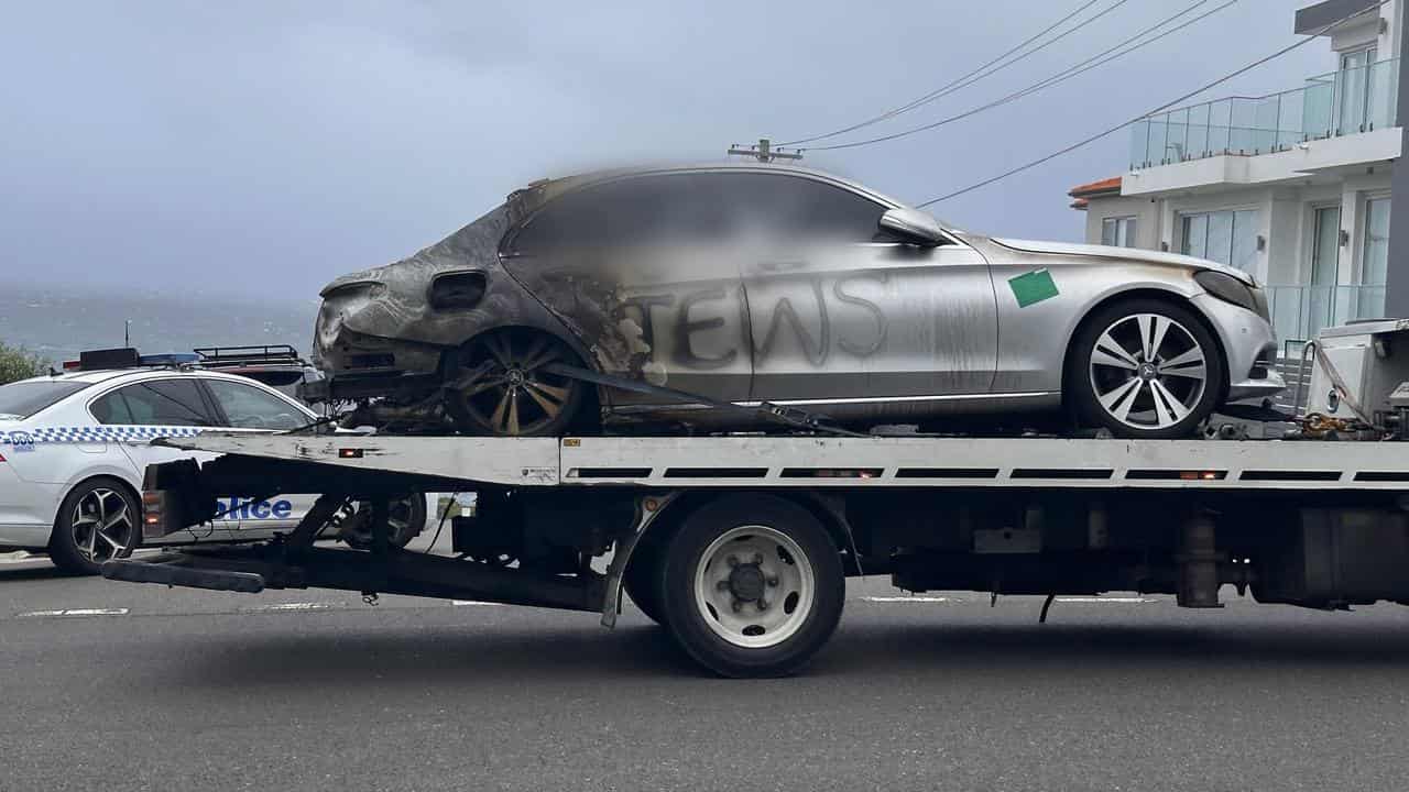 A burnt out car with anti-Semitic graffiti (blurred image)