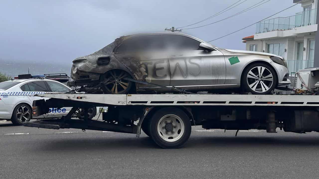 A burnt-out car is towed away