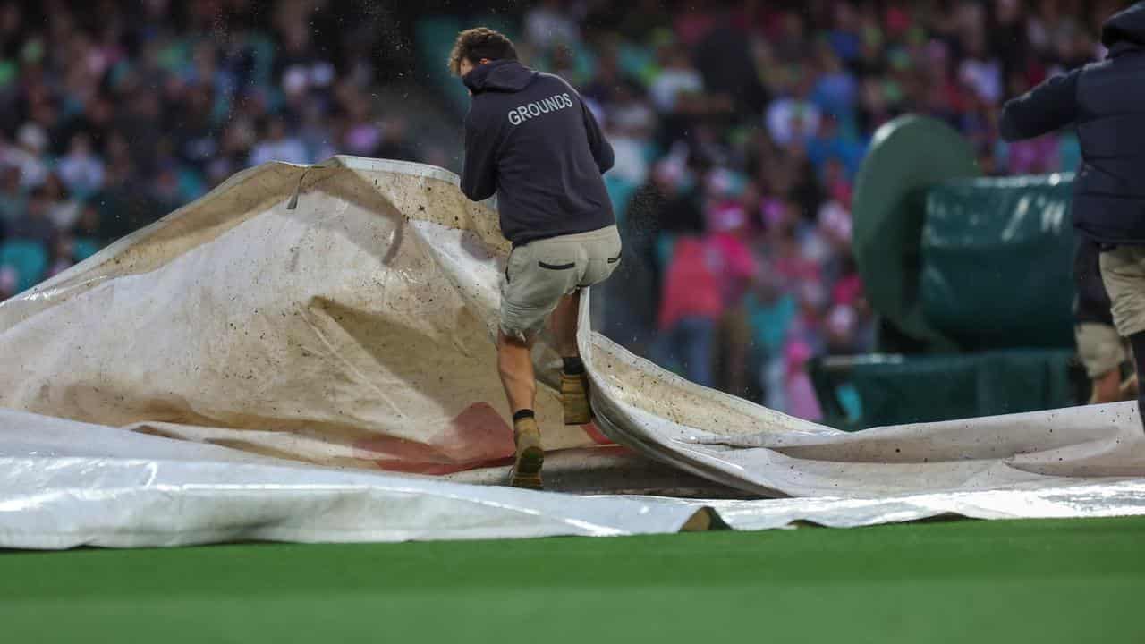 SCG groundstaff grapple with covers in the wind.