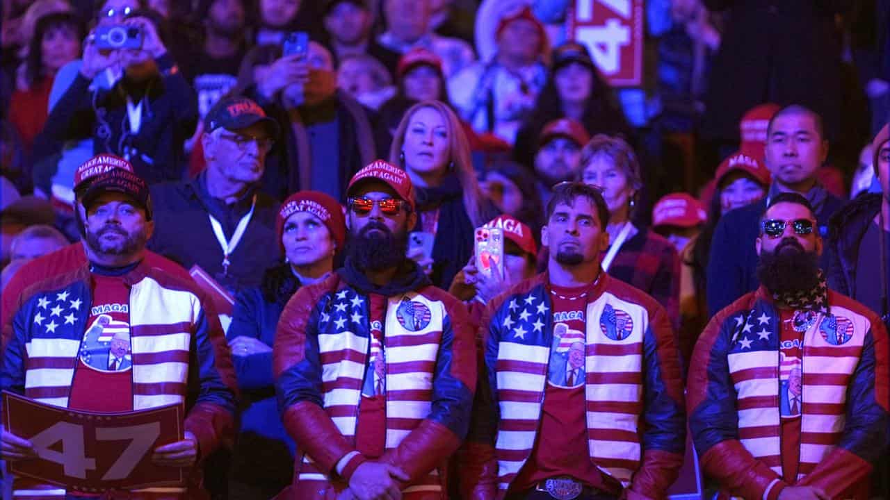 People watch as President-elect Donald Trump speaks at a rally