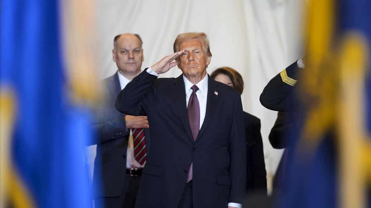 President Donald Trump salutes while on stage in