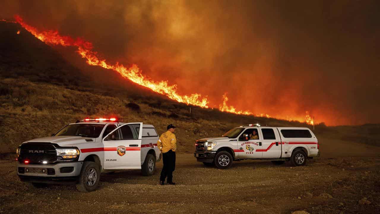 Firefighters monitor flames caused by the Hughes Fire in Castaic