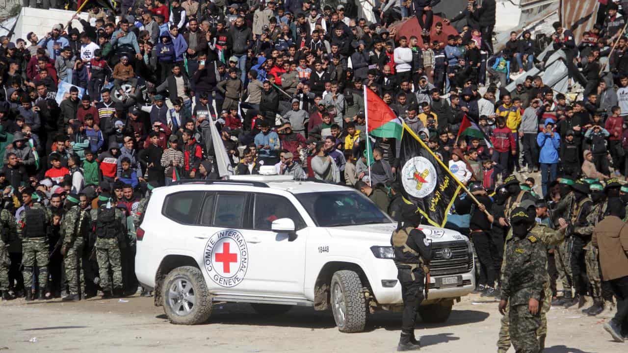 Crowds of Palestinians and a Red Cross vehicle